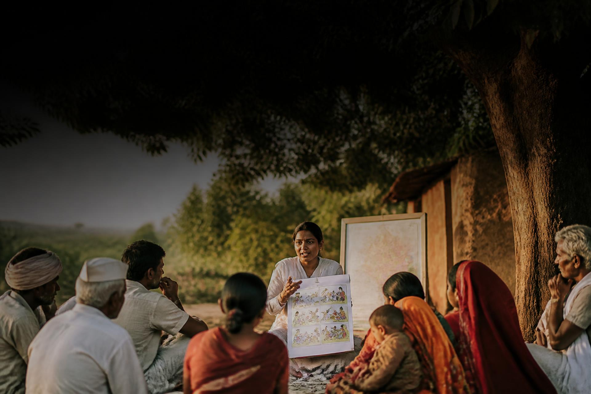 A community health worker leads a snakebite awareness session with villagers
